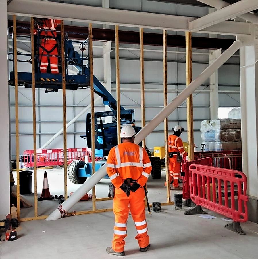 Operatives building a timber stud wall with a boom lift inside the Alyth substation building