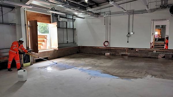 Operative applying floor sealer with a roller in a large open hall