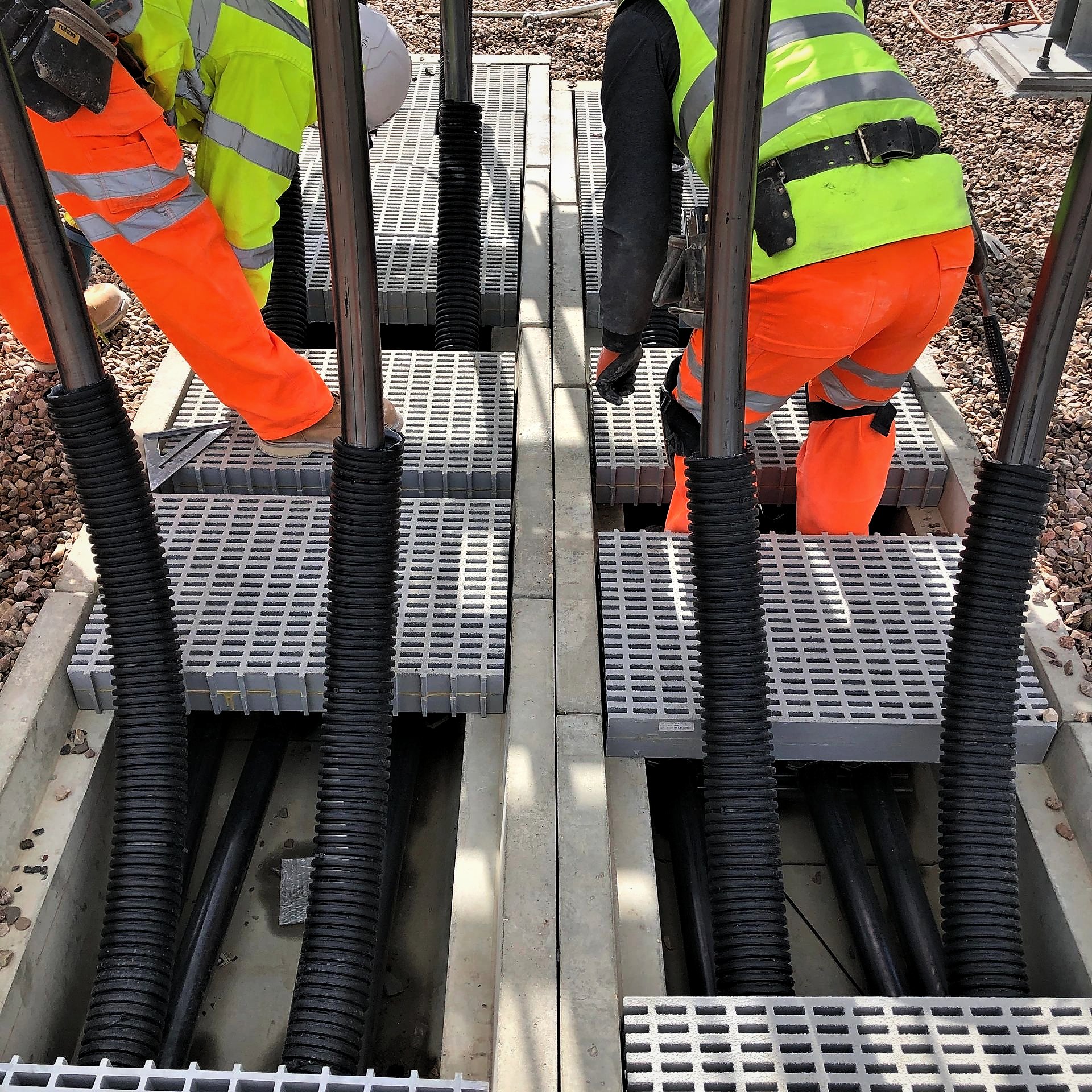 Operatives fitting grating covers over cable troughs at a substation