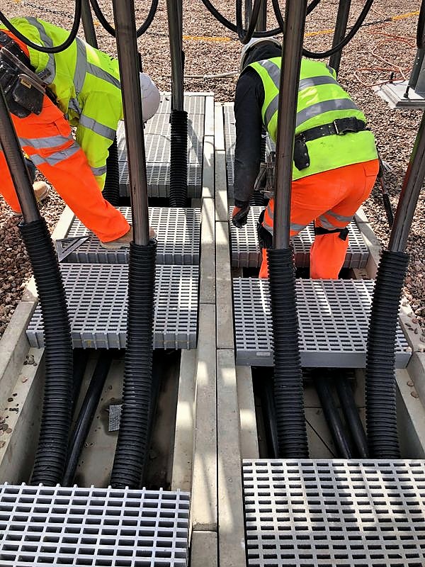 Operatives fitting grated covers over cable troughs at a substation