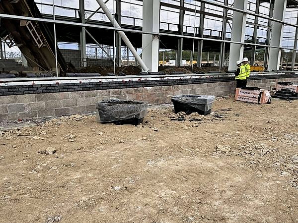Block and brick dwarf wall running the perimeter of a steel-framed building