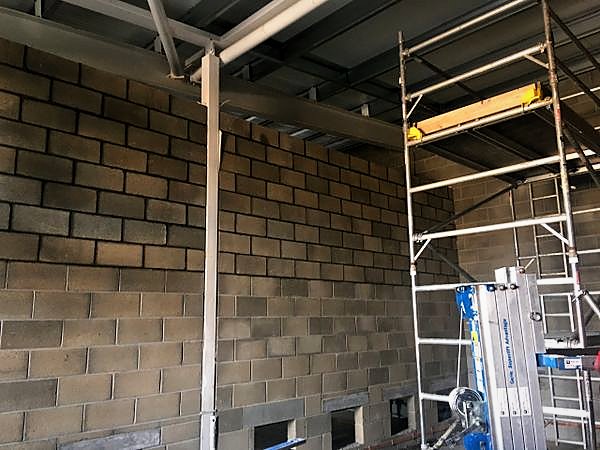 Blockwork infill wall between steel columns with a mobile tower alongside