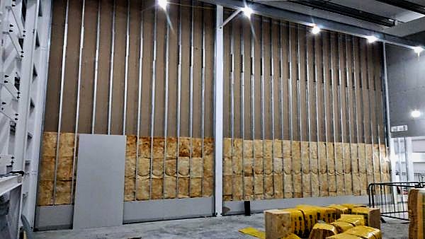 Full-height stud partition with insulation in a steel-framed hall