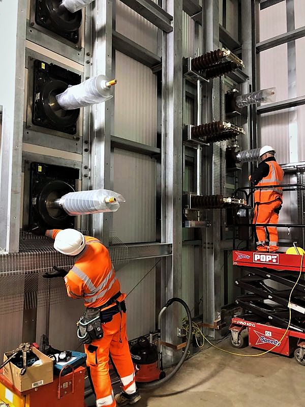 Operatives working from scissor lifts inside an HV equipment hall