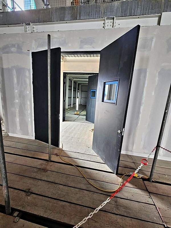 Heavy steel double doorset hung and opening onto a timber walkway