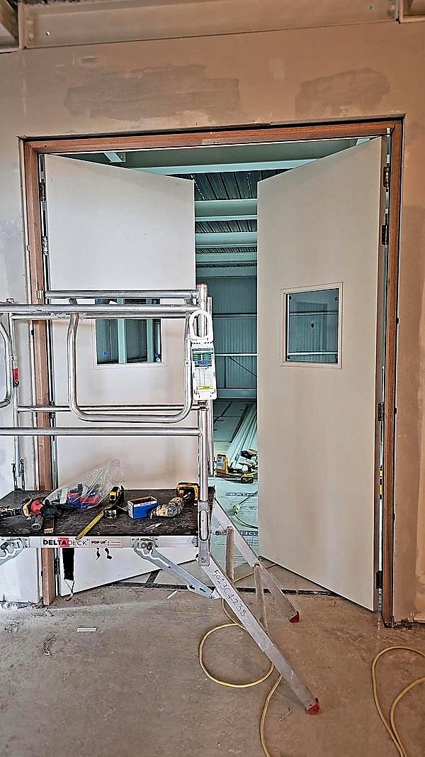 Internal double doorset being hung, with tools set out on a podium platform