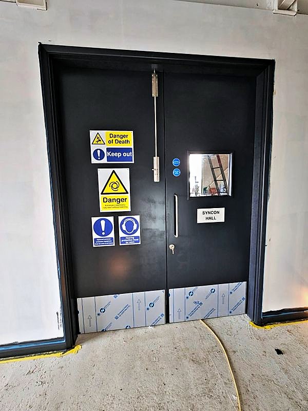 Finished steel double doors to a syncon hall with statutory safety signage