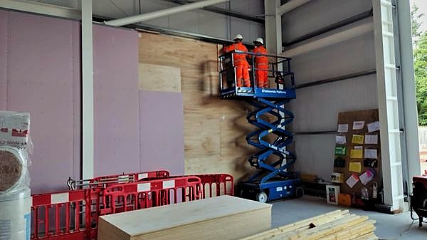 Operatives fixing plywood lining alongside boarded partitions