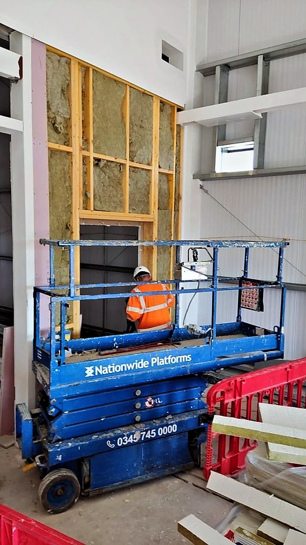 Insulated stud framing around an opening with a scissor lift in front