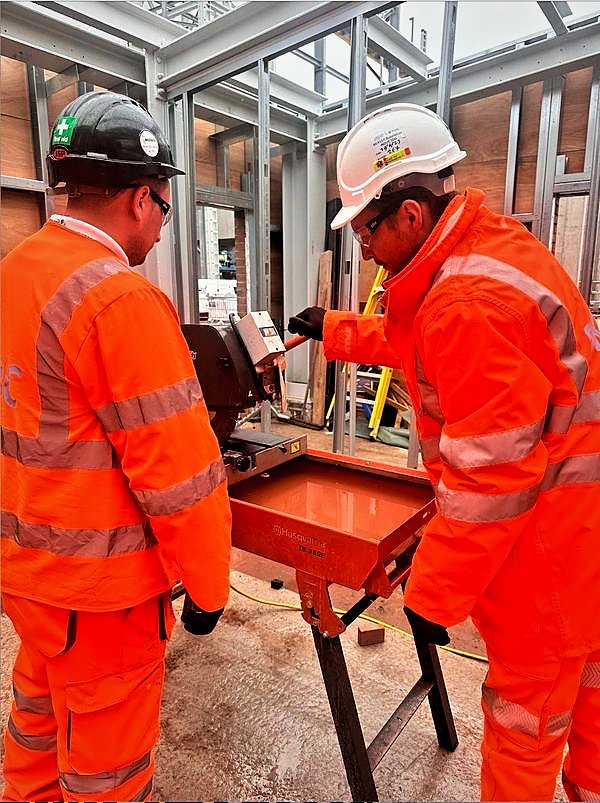 Two operatives cutting masonry on a bench saw within light gauge steel framing