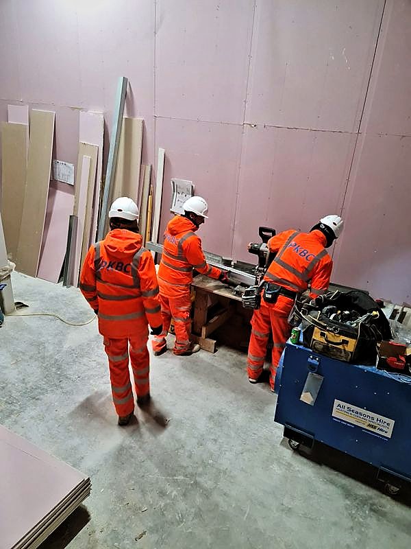 PKBC operatives cutting studs at a bench inside a boarded room
