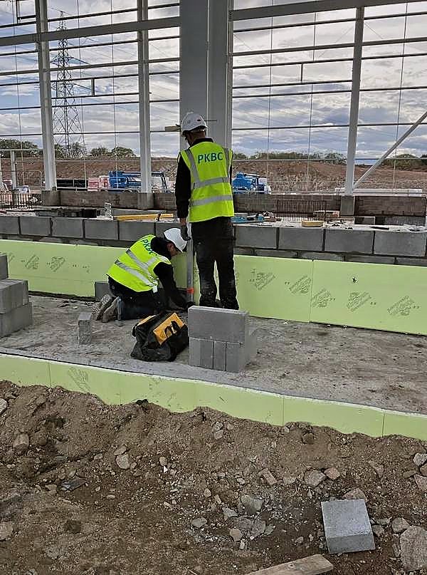Two PKBC operatives setting out blockwork off a concrete upstand