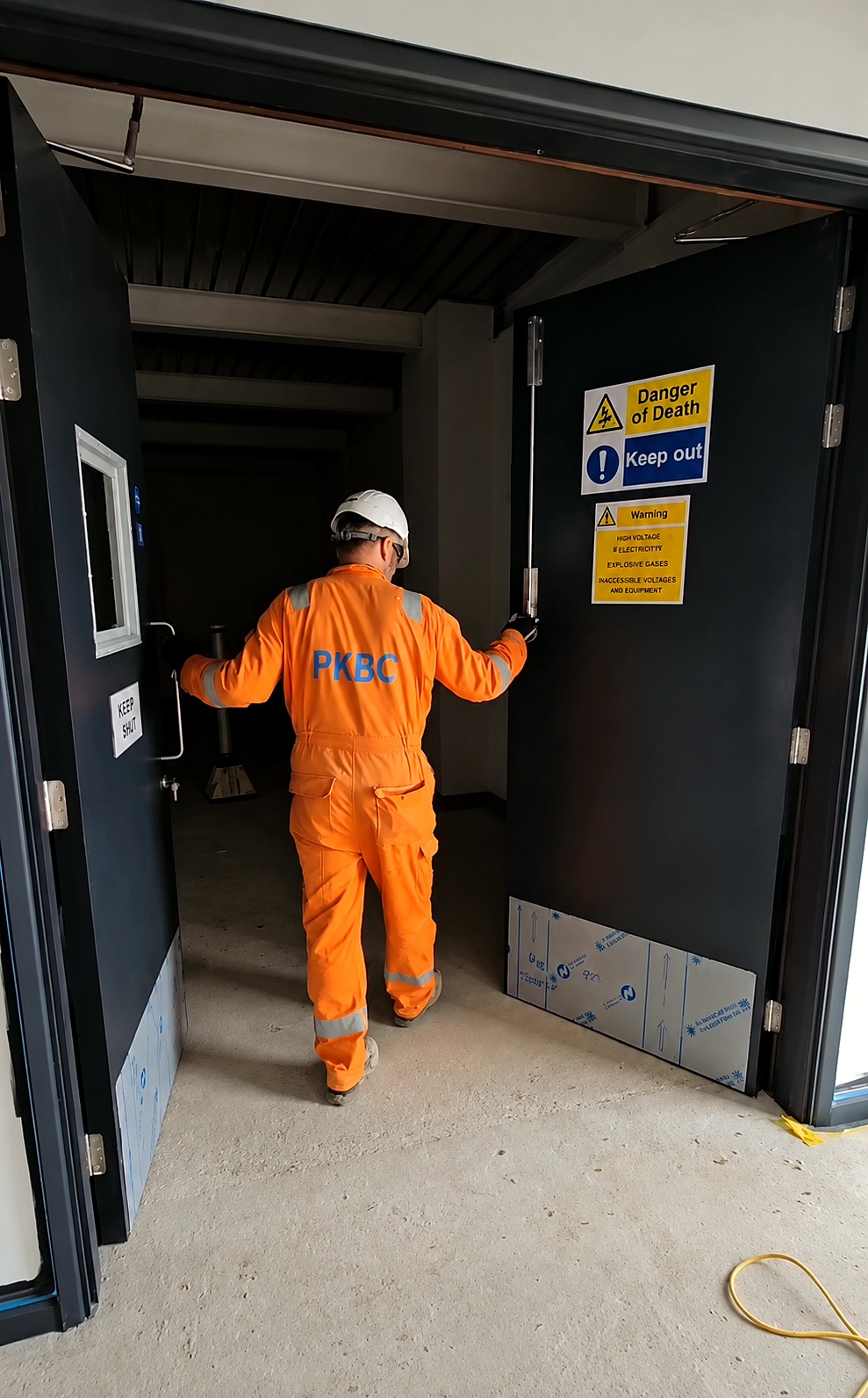 PKBC operative passing through newly installed fire doors marked Danger of Death at the Eye grid stability facility