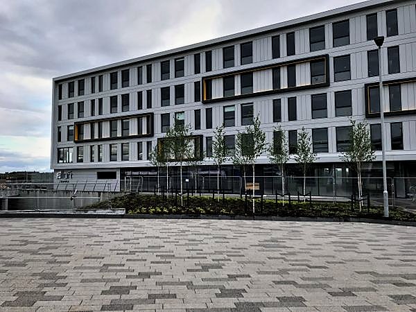Completed multi storey building with panel cladding, new planting and paving
