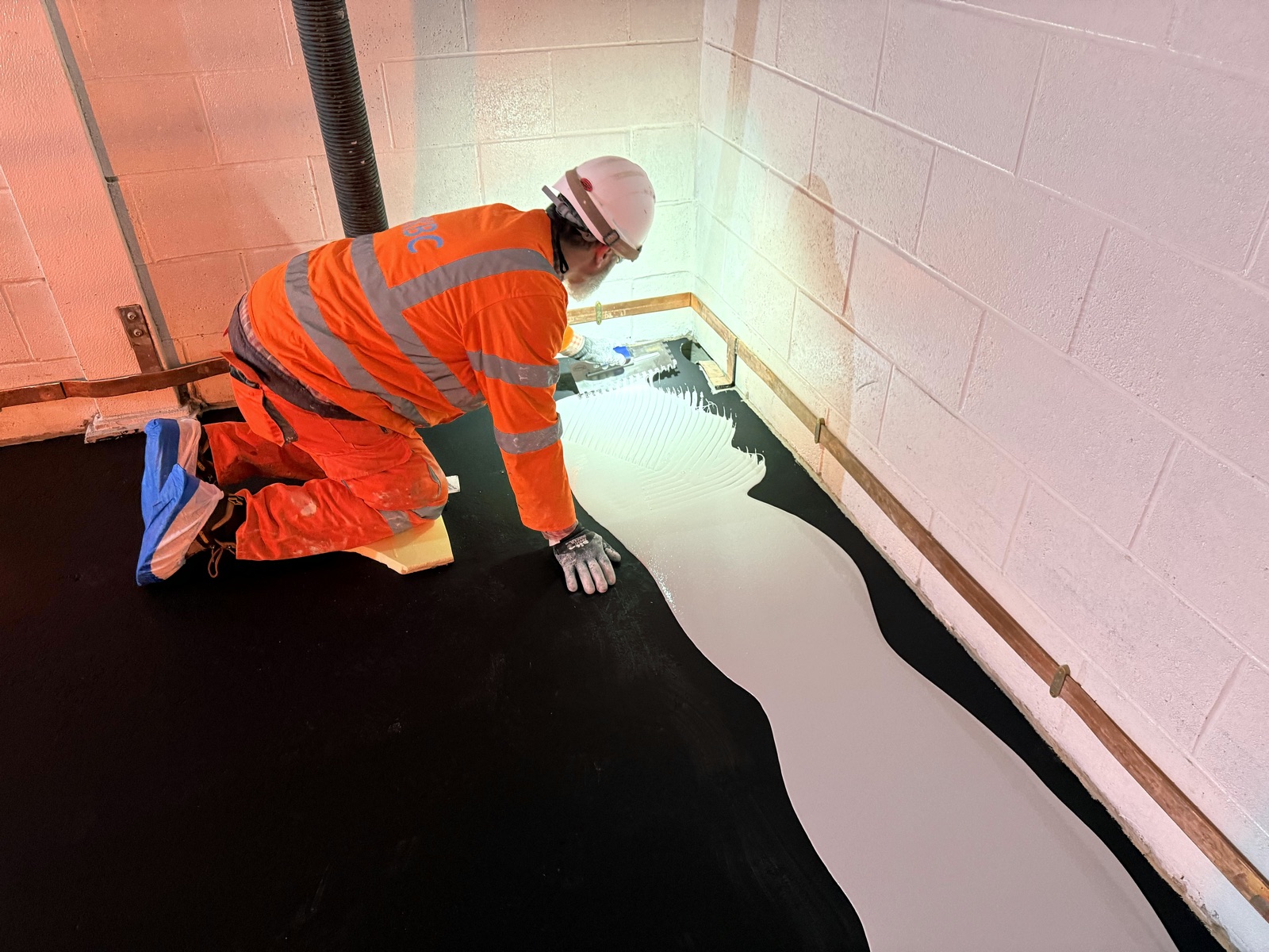 PKBC operative applying resin floor coating with a notched trowel at the Gremista substation