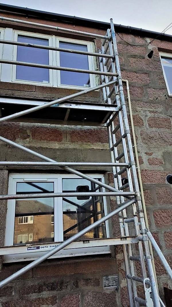 Alloy tower scaffold mounted for window replacement on a granite house