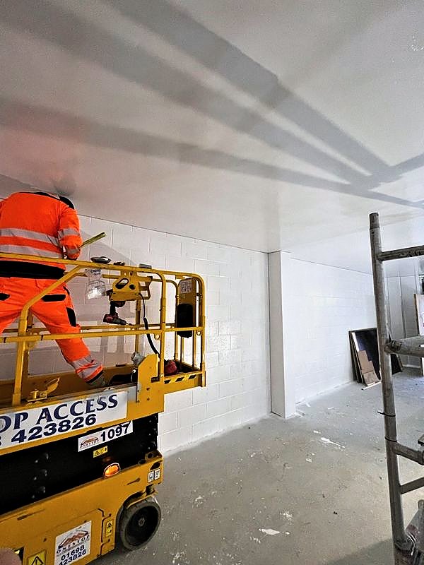 Operative on a scissor lift finishing the wall head of a painted room