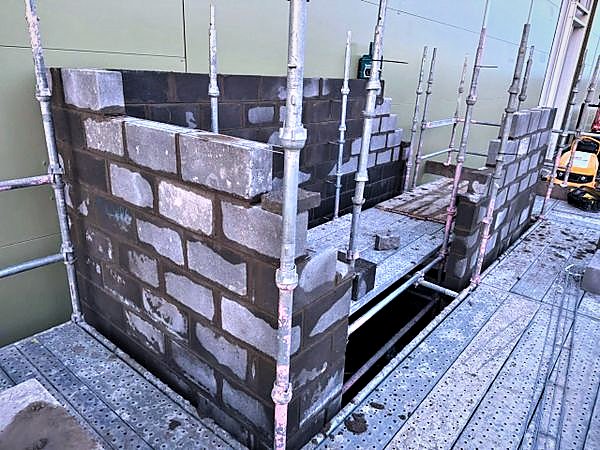 Blockwork enclosure rising through a scaffold crash deck