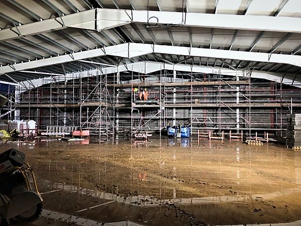 Scaffold lifts along blockwork walls inside a steel portal frame during night works