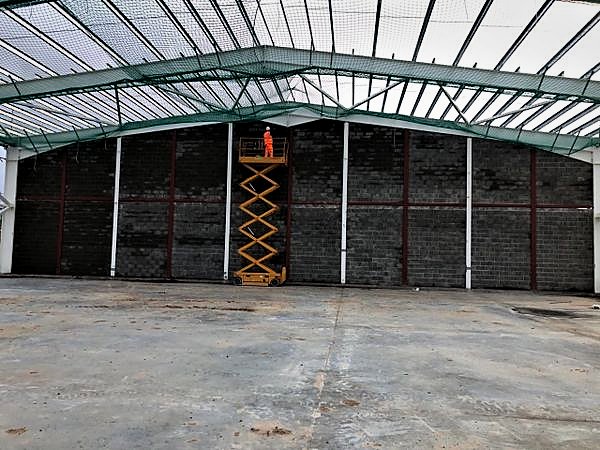 Operative on a scissor lift against a full-height blockwork gable