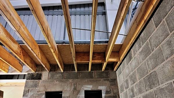 Timber joists spanning a blockwork structure inside a steel framed hall
