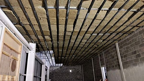 Insulation and resilient bars fixed across a ceiling between blockwork walls