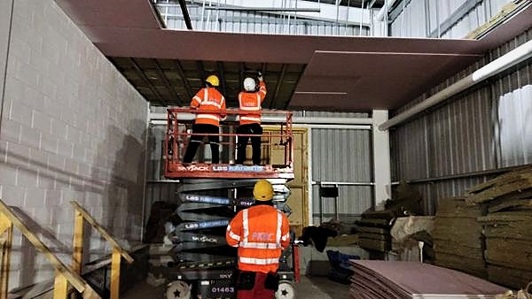 Operatives boarding a ceiling bulkhead from a scissor lift