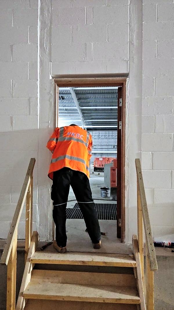 PKBC joiner fitting a timber door lining beside a new timber staircase