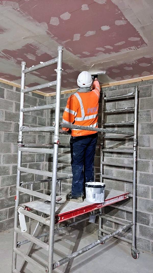 Operative on a tower scaffold jointing a ceiling ready for decoration