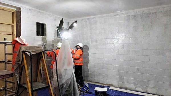 Operatives spray-applying a protective coating to blockwork walls