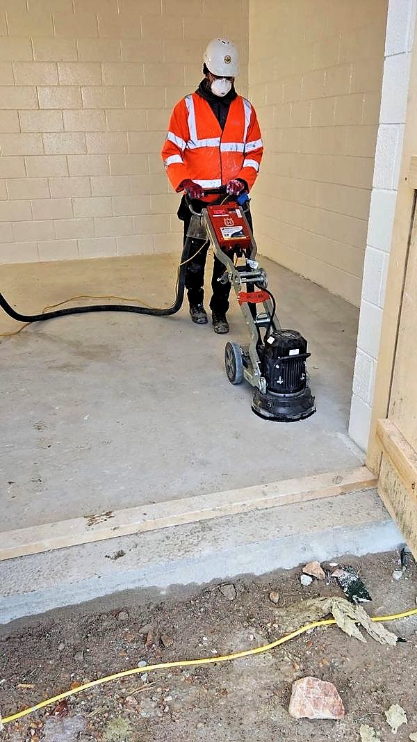 Operative grinding a concrete slab with dust extraction before coating