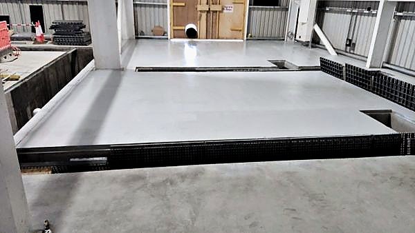 Coated floor slab cast over open service trenches inside an industrial building