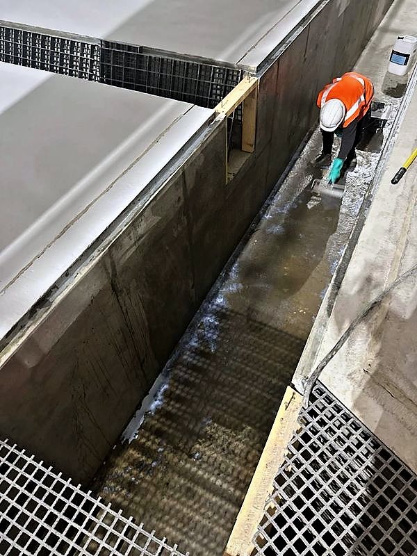 Operative preparing the base of a concrete channel beside GRP grating before coating