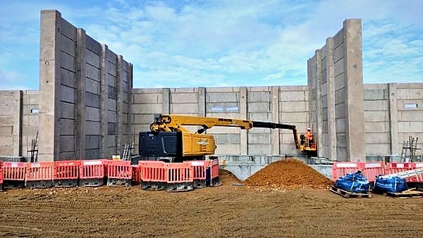 Precast substation walls under construction with a boom lift placing an operative at height