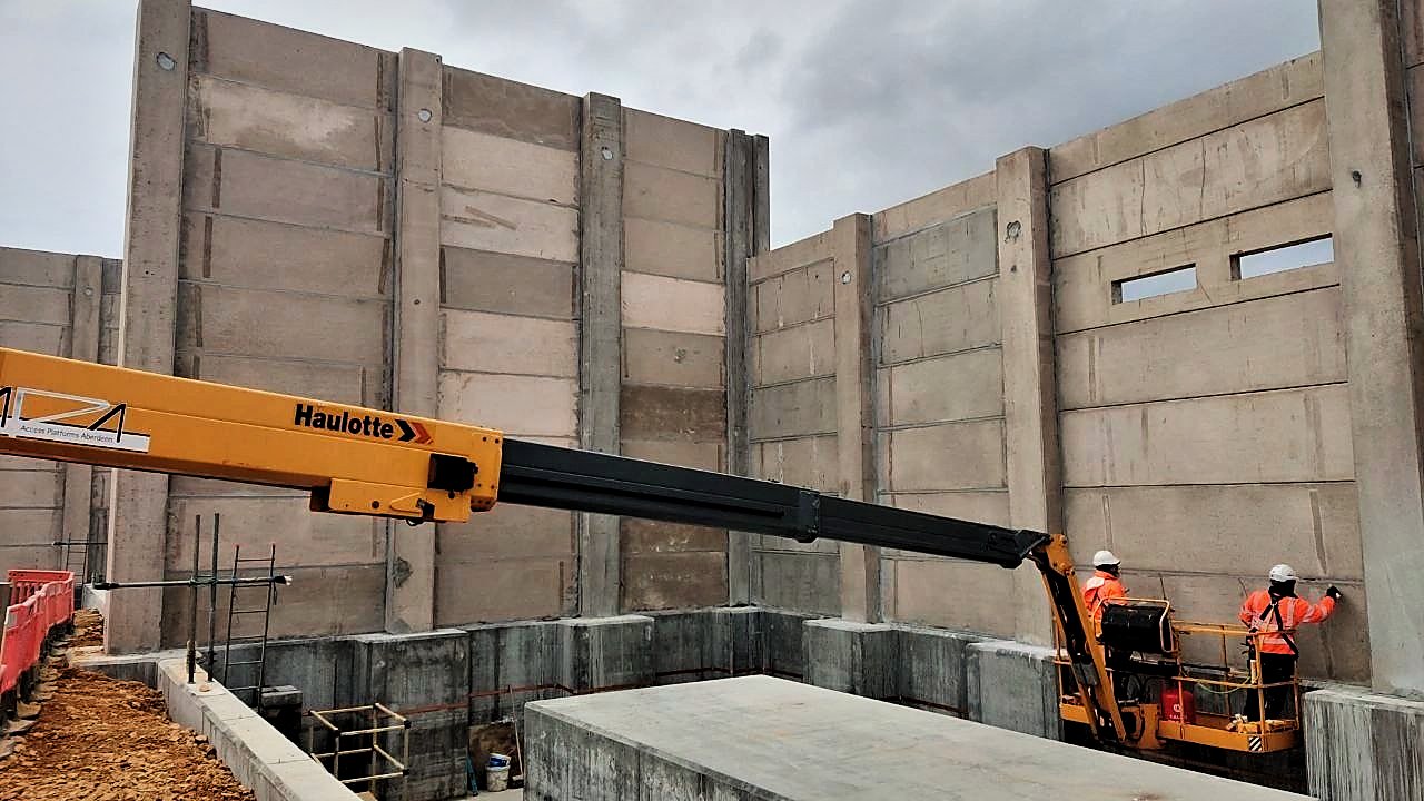 Operatives working from a boom lift against precast concrete substation walls