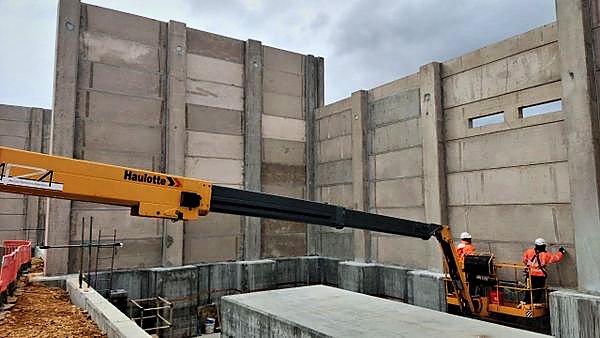 Telescopic boom working against precast concrete substation walls with operatives at the wall head