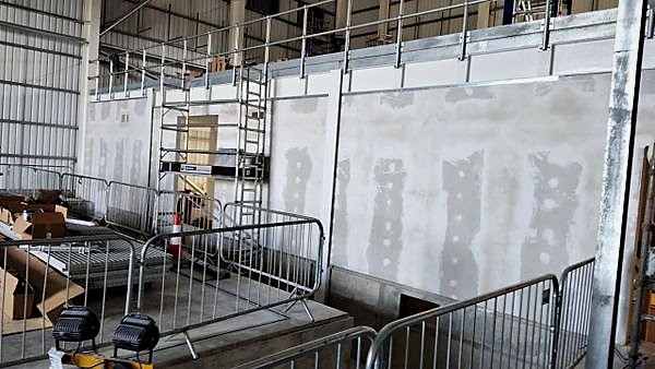 Plasterboard partitions being prepared for decoration inside an industrial hall