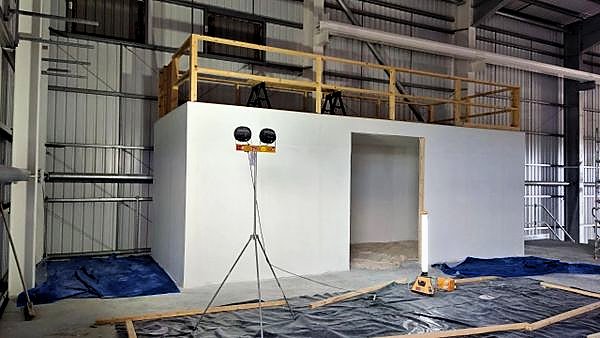 Freshly painted white enclosure inside a steel-framed industrial hall