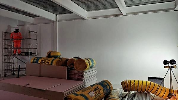 Operative on a tower scaffold in a room with completed wall linings