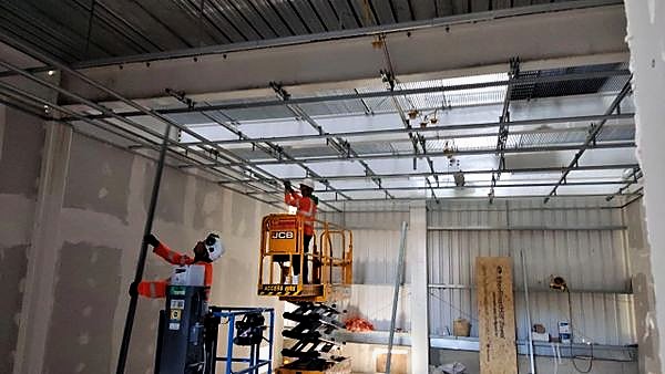Suspended ceiling grid being installed from powered access