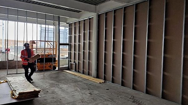 Operative carrying insulation past metal stud partitions ready for boarding