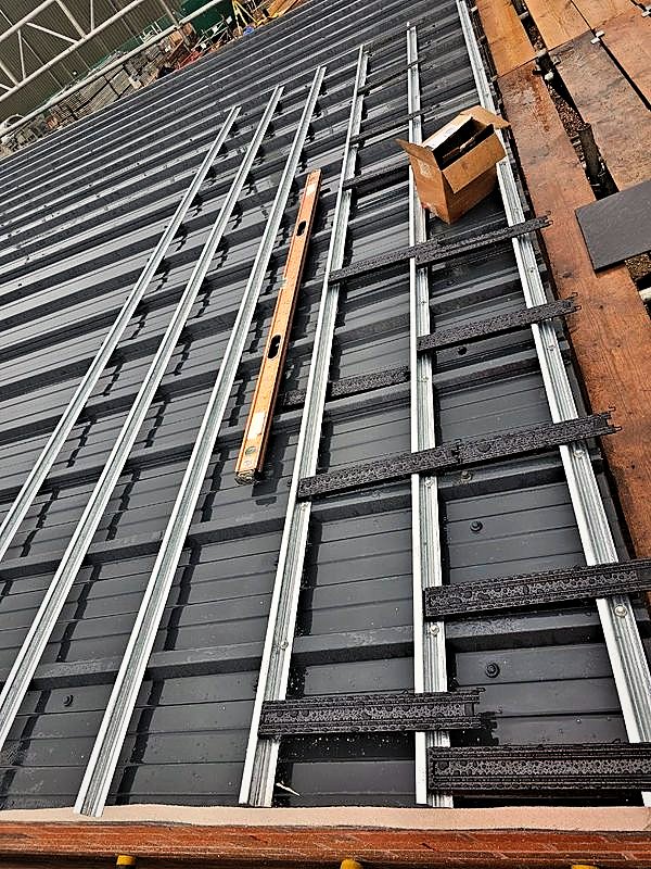 Roof rails and brackets set out across standing seam roof sheets