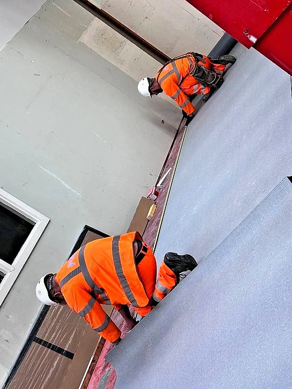 Operatives fitting sheet flooring in a commercial unit