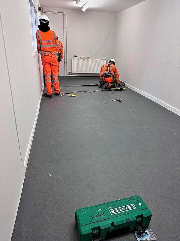 Operatives installing vinyl flooring in a refurbished room