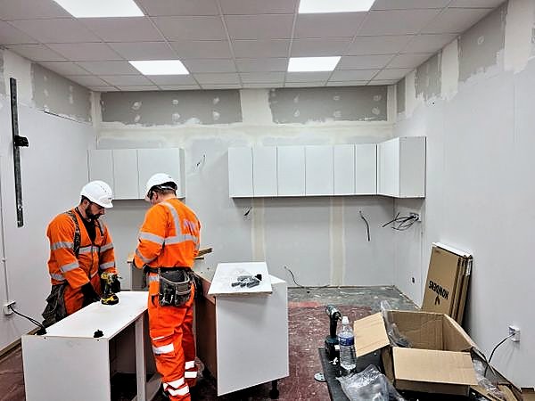 PKBC operatives assembling white cabinet units during a commercial fit-out