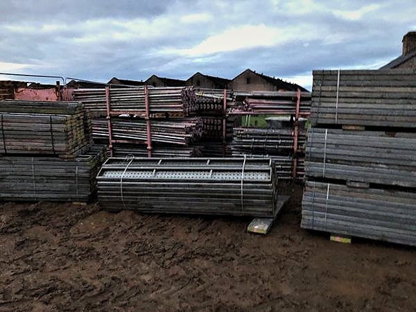Racked scaffold tube, boards and battens stacked in the site compound