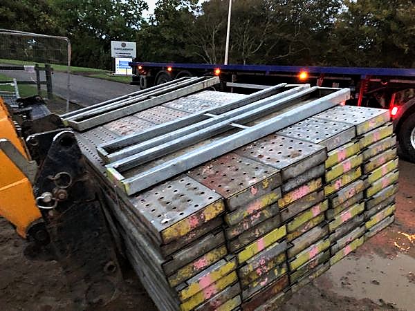 Telehandler moving stacked steel battens to a flatbed trailer for despatch