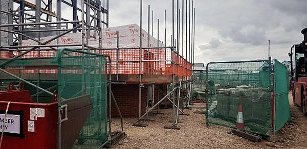 Scaffold and edge protection around a membrane-wrapped structure on a fenced compound