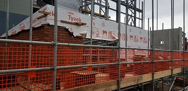 Scaffold with barrier netting around facing brickwork and a fire-rated breather membrane