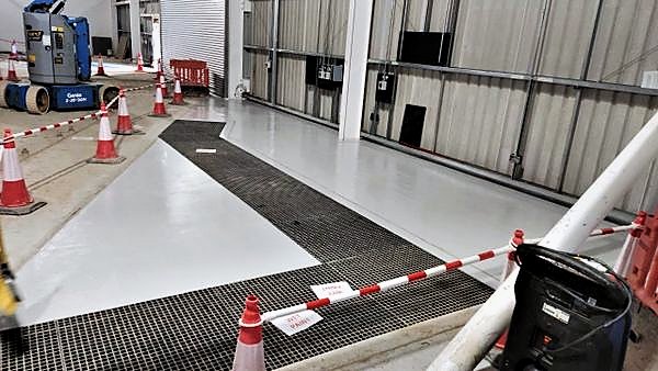 Freshly applied floor coating with wet paint signage around access grating